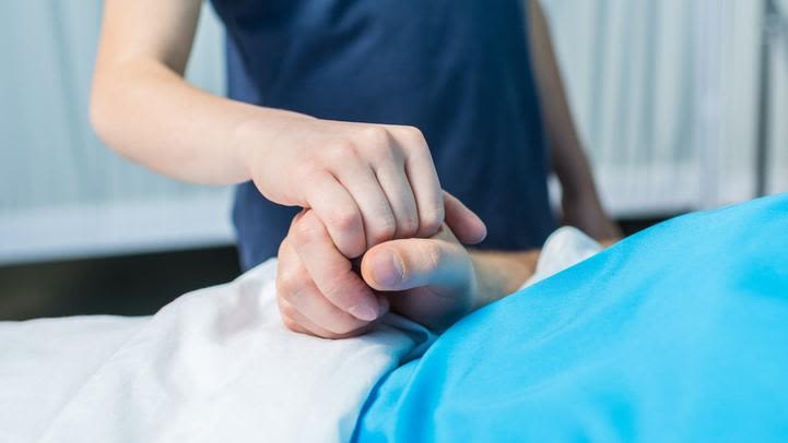 Child linking hands with parent in hospital