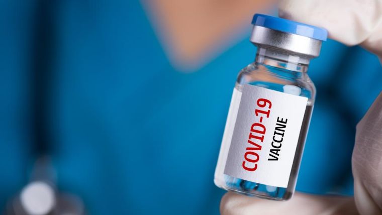 A bottle of COVID-19 vaccine held by a health professional