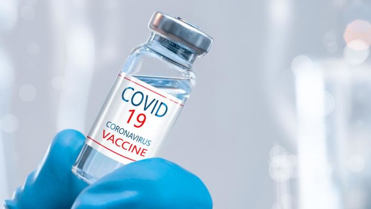 Coronavirus vaccine concept in blue jar in hand of doctor