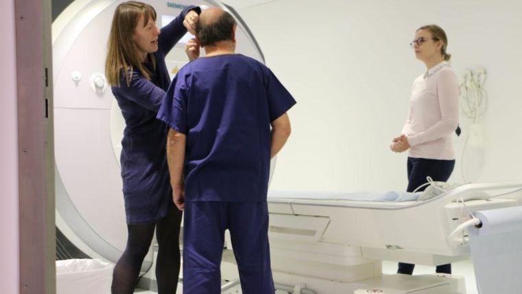 A patient and two staff standing by the MRI scanner in the Brain Health Centre.