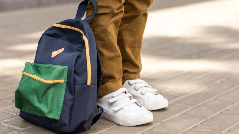 A young person's legs, shoes and school bag