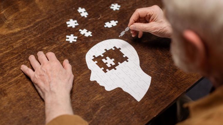 A man assembles a jigsaw in the shape of a head