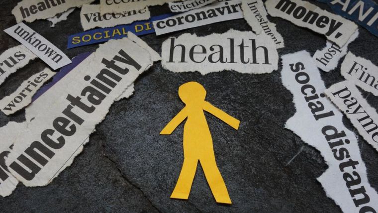 Image shows paper cut out of a person surrounded by newspaper clippings with the caption: health, uncertainty, social distancing and money etc.