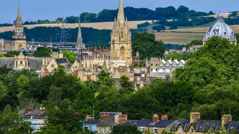Landscape image of Oxford spires with hills in the backdrop.