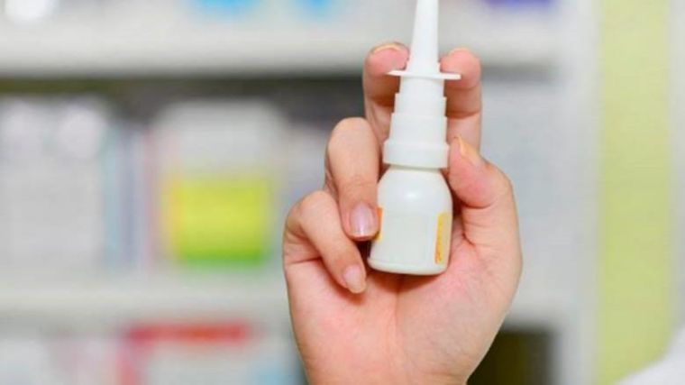 image shows hand holding a nasal spray which administers the drug.