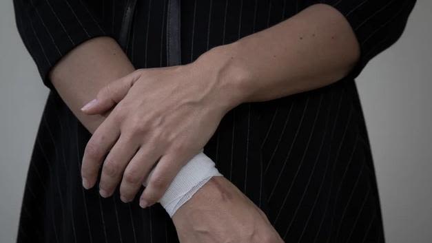 Image shows someone holding their bandaged wrist.