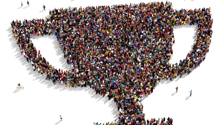 Aerial photo of a cup made out of people standing together.