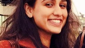 Headshot of Priyanka, female smiling at camera wearing red jacket